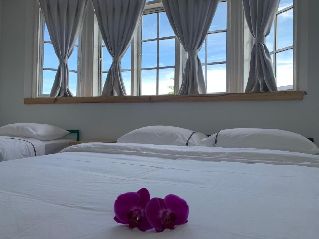 Una cama blanca con una flor morada. en The Hill at Fraser Hill, en Bukit Fraser