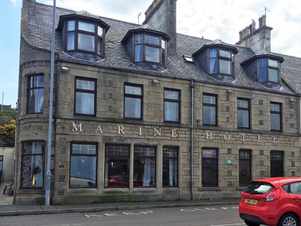 a red car parked in front of a building at Marine Hotel in Buckie
