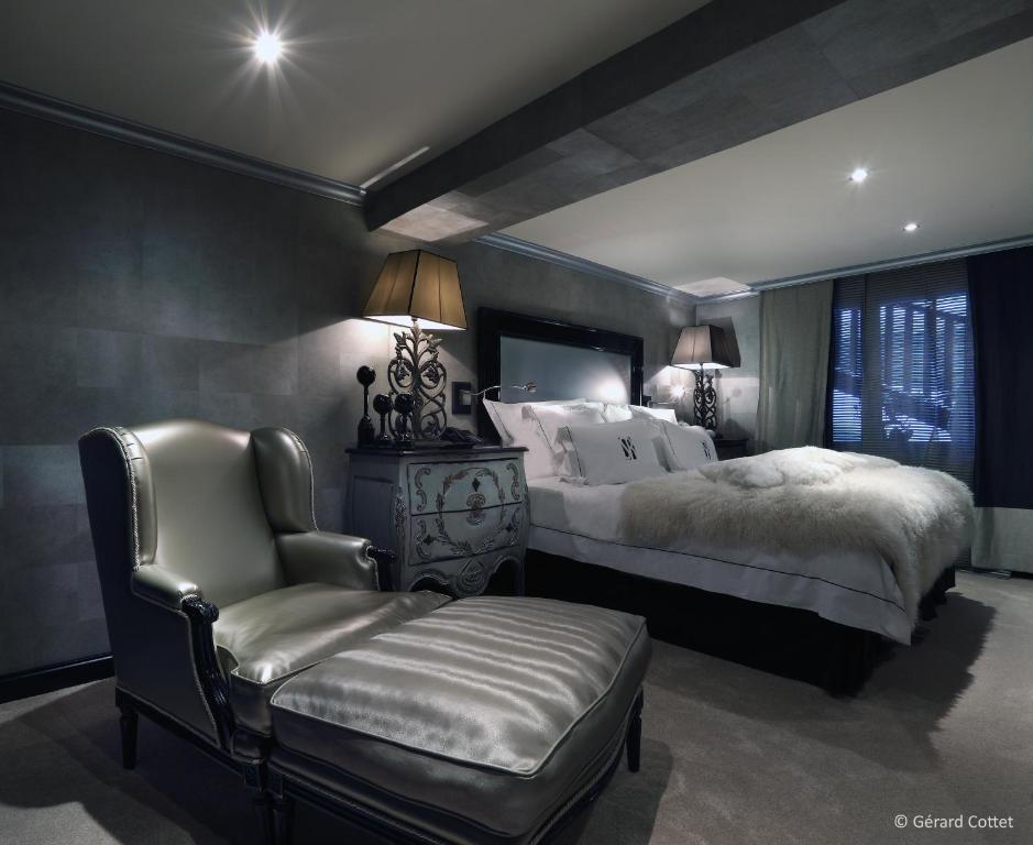 a bedroom with two beds and a chair at Hotel Le Saint Roch in Courchevel