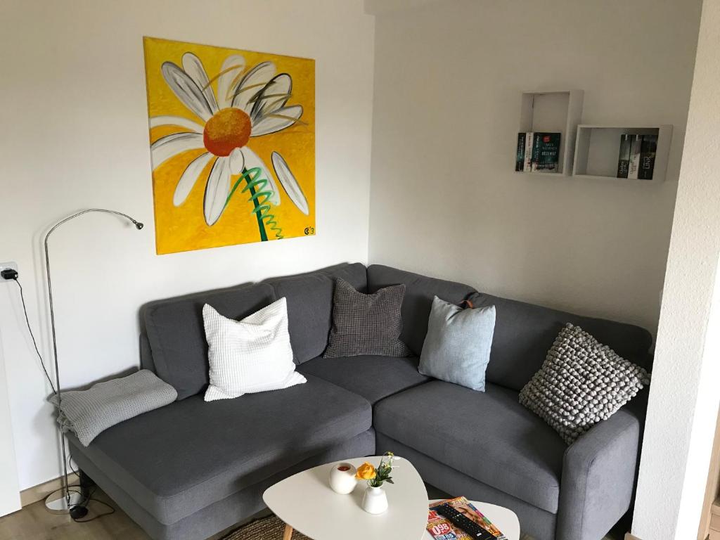a living room with a gray couch and a flower painting at Burgblick in Nideggen