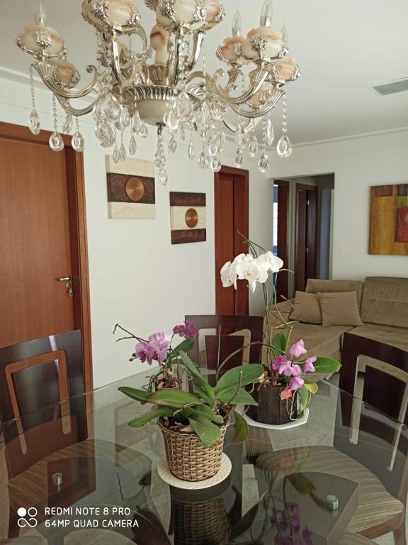 a living room with a glass table with a chandelier at Apartamento setor bueno in Goiânia