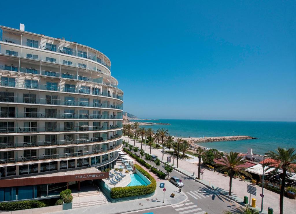 
a large white building with a balcony overlooking the ocean at Calipolis in Sitges
