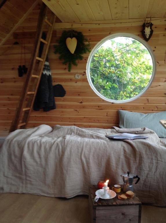 een slaapkamer met een bed en een rond raam bij Treehouse escape in Kværndrup
