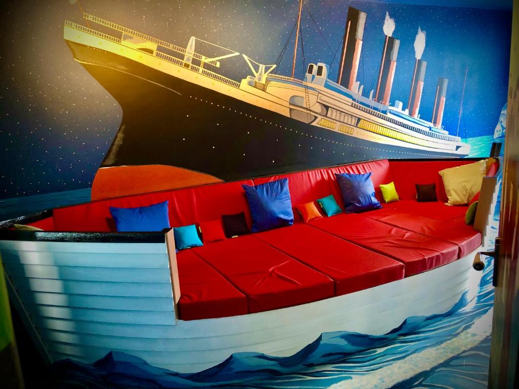 ein Zimmer mit einer roten Couch mit einem Schiff an der Wand in der Unterkunft Rose Titanic Belfast romantic world in Belfast