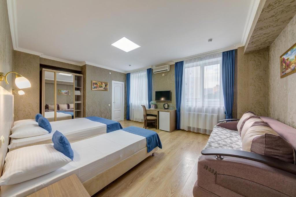 a hotel room with two beds and a desk at Atlas Hotel in Gelendzhik