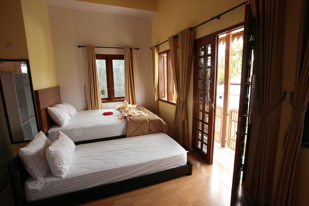 a bedroom with two beds and a balcony with windows at Grya Pyramyt in Banyuwangi