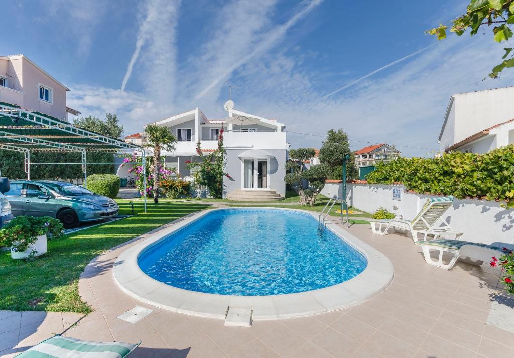 a swimming pool in the yard of a house at Apartments Manda in Vodice