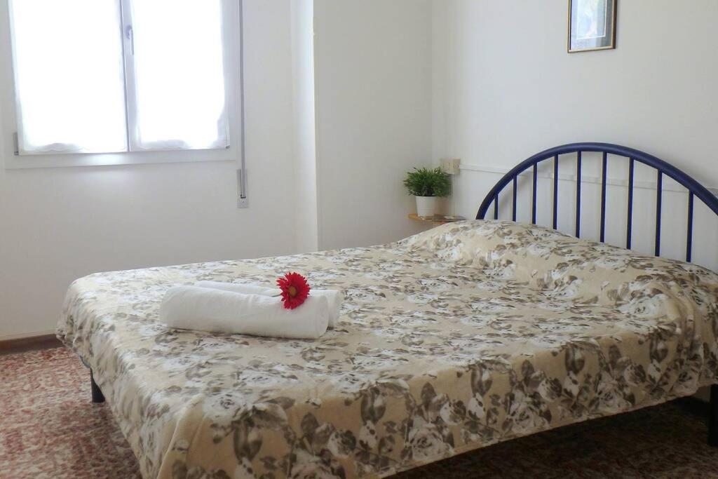 Una cama con una almohada con una flor roja. en Nettuno 1A, en Lido di Pomposa