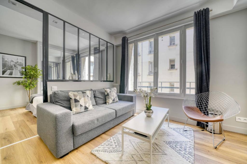 ein Wohnzimmer mit einem Sofa und einem Tisch in der Unterkunft 1628 - Loft Champs Elysées Olympic Games 2024 in Paris