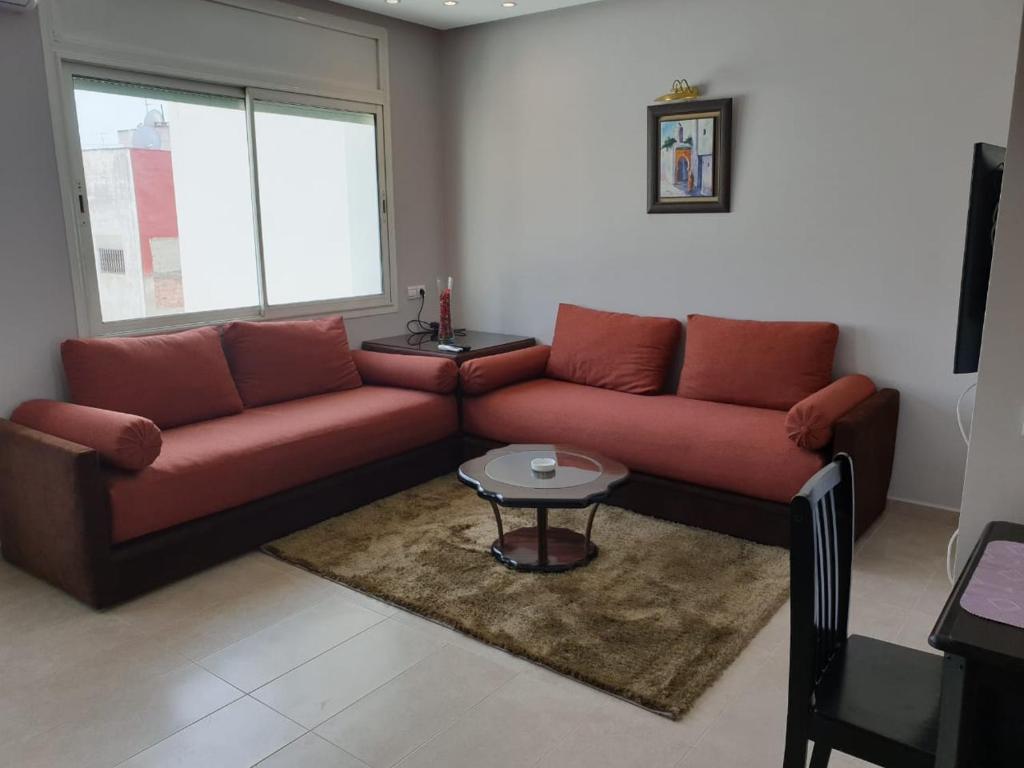 ein Wohnzimmer mit einem roten Sofa und einem Tisch in der Unterkunft Residence Davos Rabat in Rabat