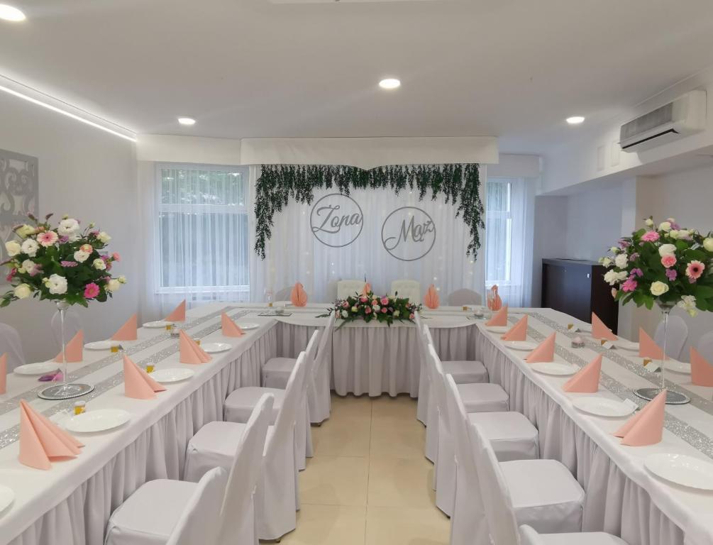 una sala banchetti con tavoli e sedie bianchi e fiori di Hotel Nad Rzeczką a Toruń