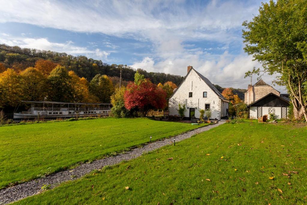 a farm with a white house and a green field at Riverside Cottage Dinant in Dinant