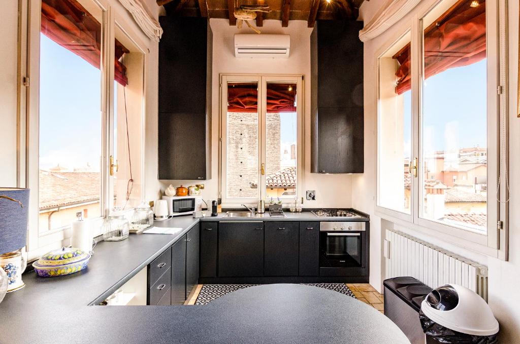 a large kitchen with black cabinets and windows at Altabella Panoramic Tower in Bologna
