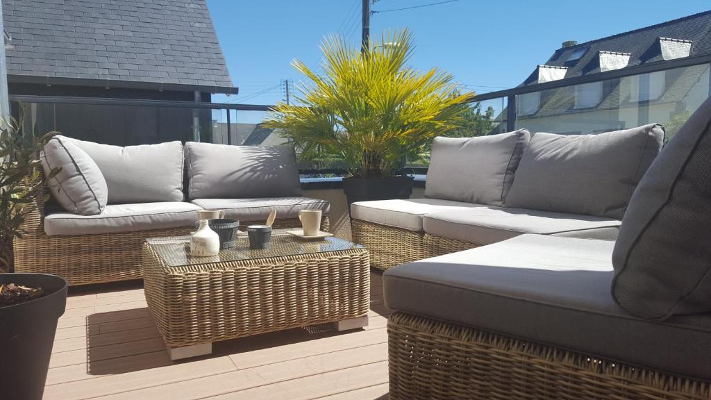 un patio avec des chaises et des canapés en osier sur un balcon dans l'établissement Les Cyprès - Appt avec terrasse proche plage, à Saint-Malo