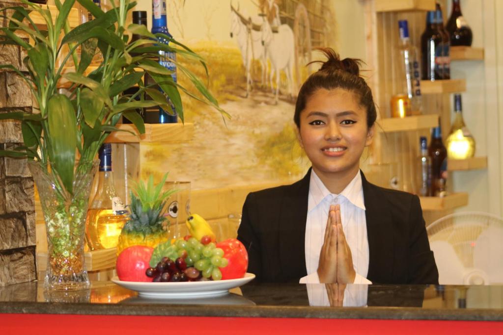 una joven sentada en una mesa con un tazón de fruta en Hotel Happy Home en Chitwan