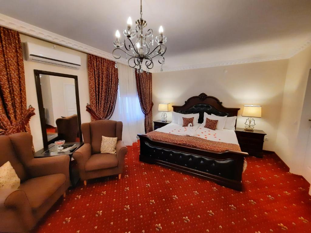 a bedroom with a bed and two chairs and a chandelier at Select House in Sibiu