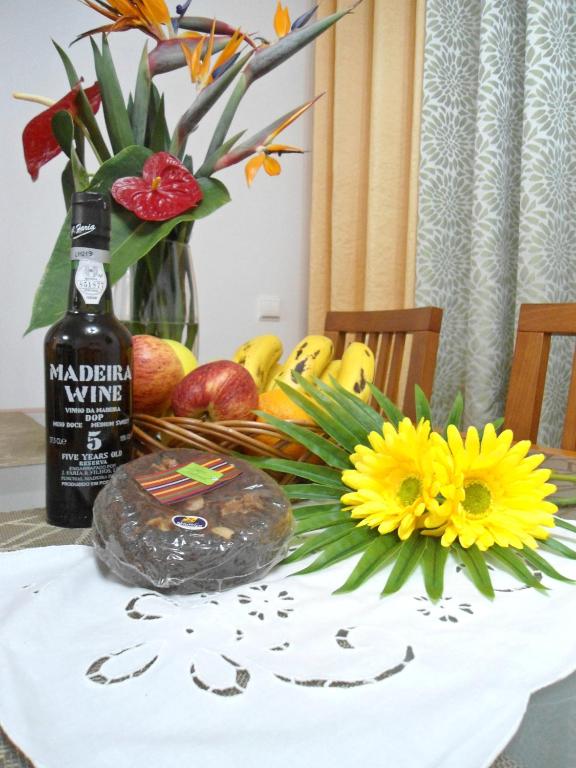 a table with a bottle of wine and a bouquet of flowers at Garden's Apartment in Funchal