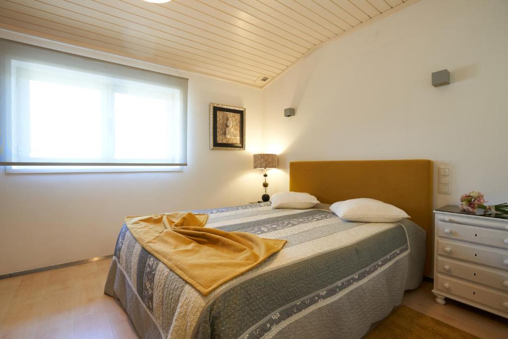 a bedroom with a bed and a window and a dresser at Host In Olivença in Vila Nova de Famalicão