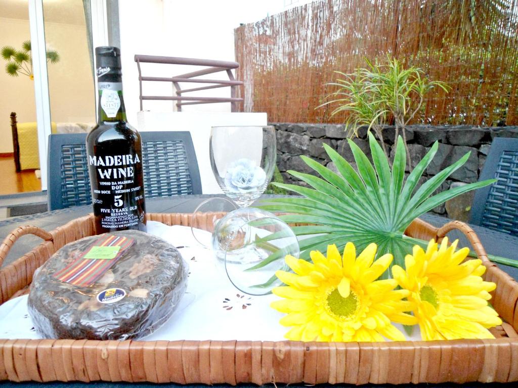 a bottle of wine and flowers on a table at Garden's Apartment in Funchal