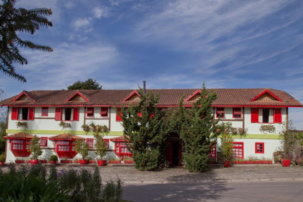 a large white building with red shuttered windows at Pousada Benevento in Campos do Jordão