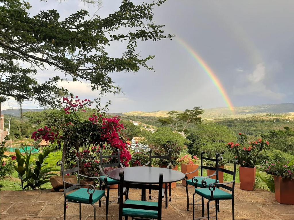 een tafel en stoelen met een regenboog op de achtergrond bij Artepolis in Barichara