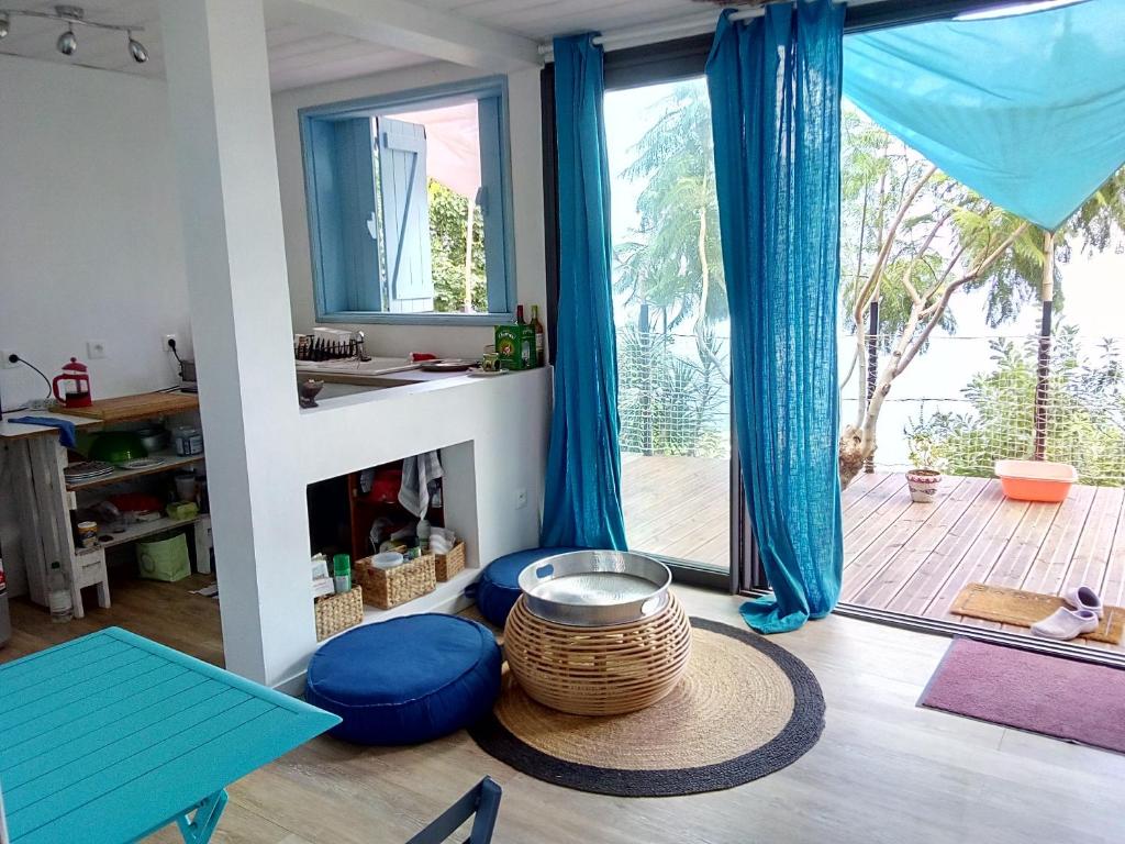 uma sala de estar com uma grande janela e cortinas azuis em Bungalow d'une chambre avec vue sur la mer piscine partagee et jardin clos a Saint Leu a 7 km de la plage em Saint-Leu