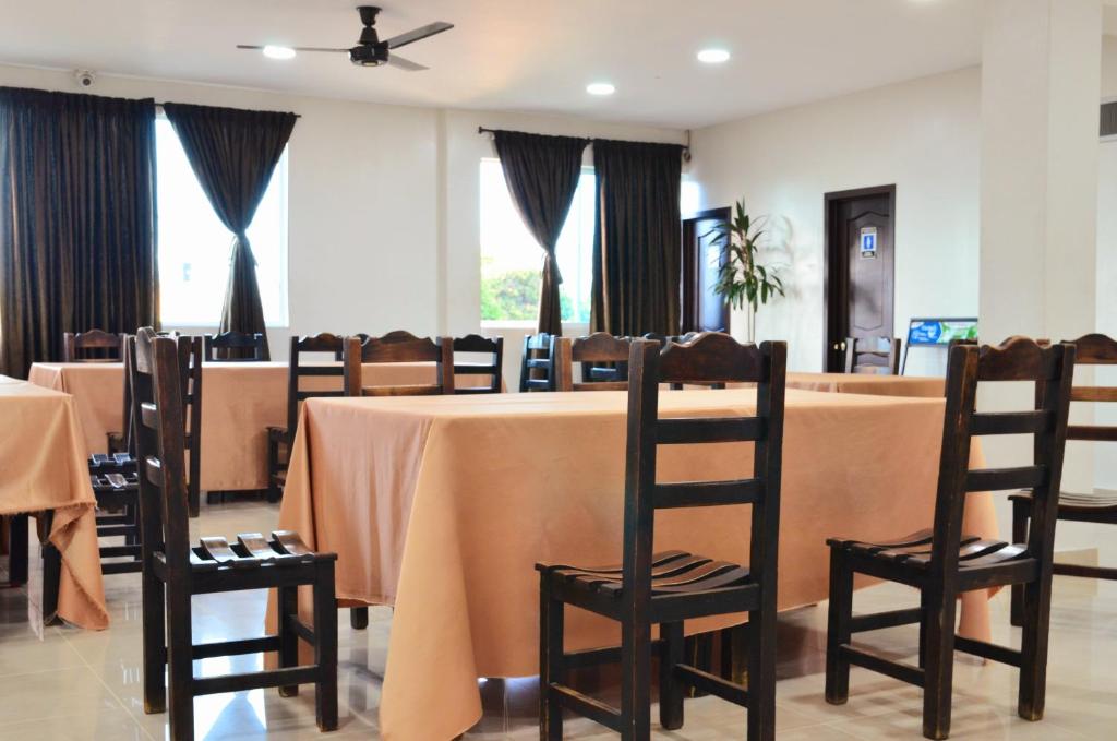 een eetkamer met een tafel, stoelen en ramen bij Hotel Diamante Real Cienaga in Ciénaga