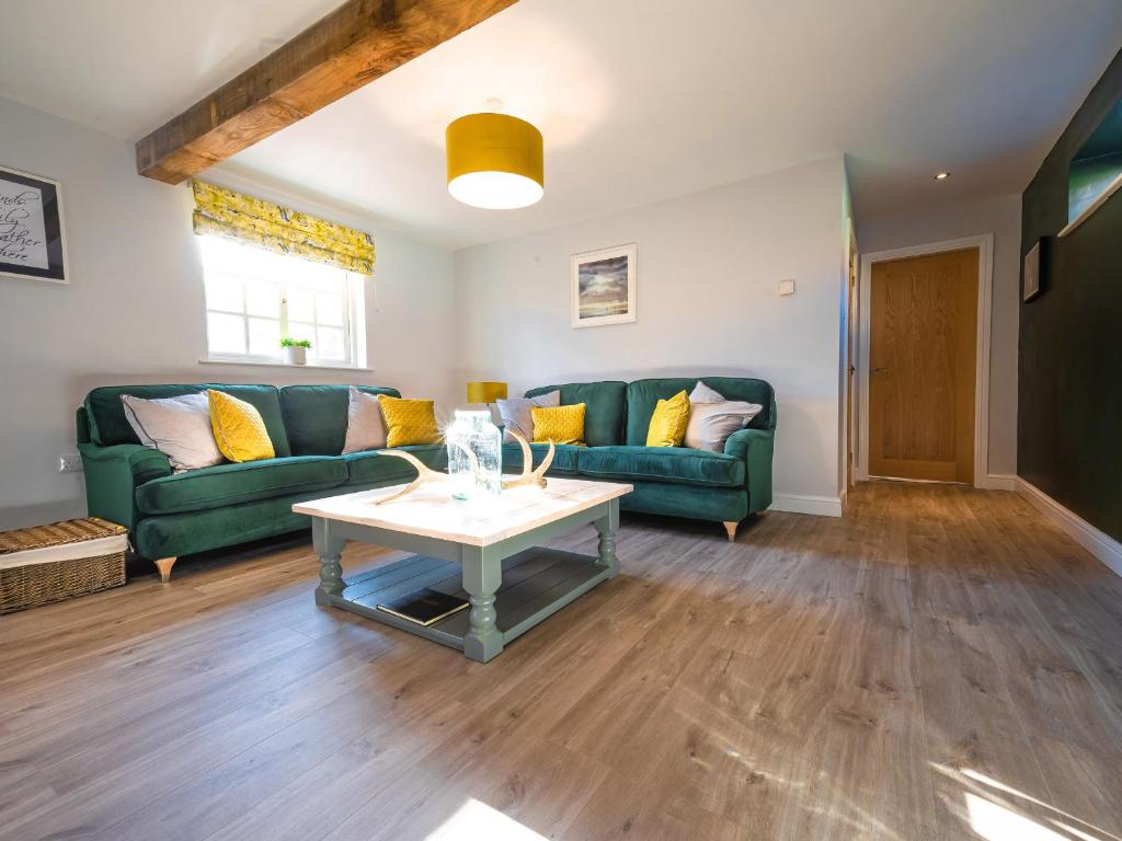 a living room with two green couches and a table at Farmcourt Barn 57 Eastfield Lane in Lincoln