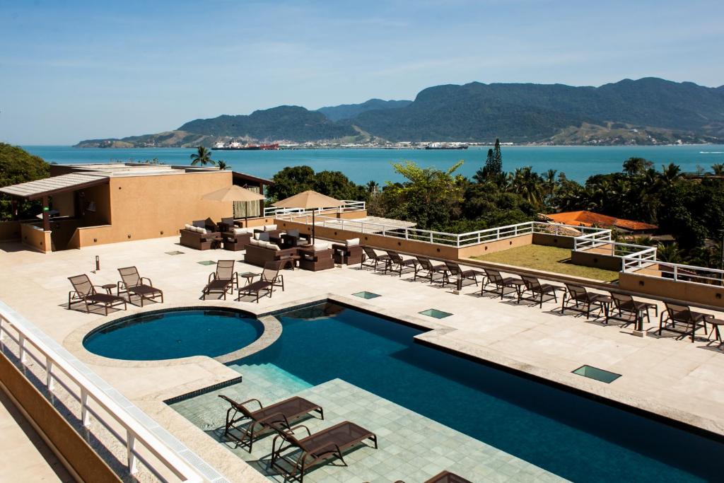 un complexe avec une piscine et une vue sur l'eau dans l'établissement Ilhabela Beach Residences, à Ilhabela