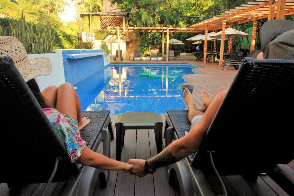 duas pessoas sentadas em cadeiras perto de uma piscina em Maya Tulipanes Express em Palenque