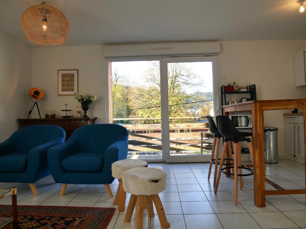 d'un salon avec des chaises bleues et une porte coulissante en verre. dans l'établissement Appartement Les Papillons plein centre ville Gerardmer, à Gérardmer