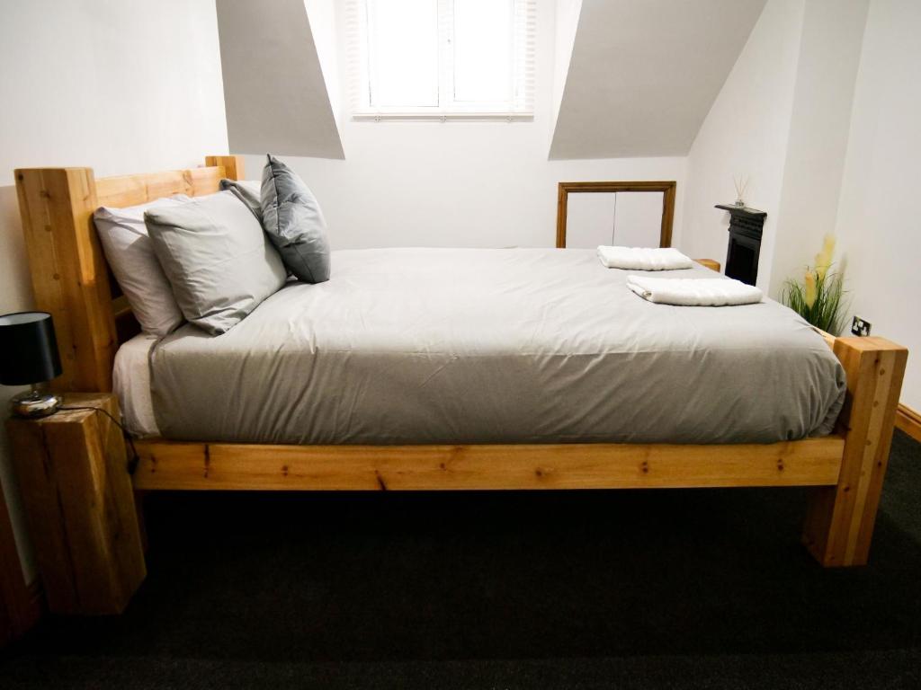 una camera da letto con letto in legno, lenzuola e cuscini bianchi di The Stone House a Nottingham