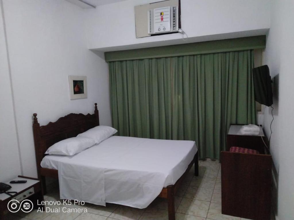 Hotel Atlântico Avenida في ريو دي جانيرو: غرفة نوم بسرير وستارة خضراء