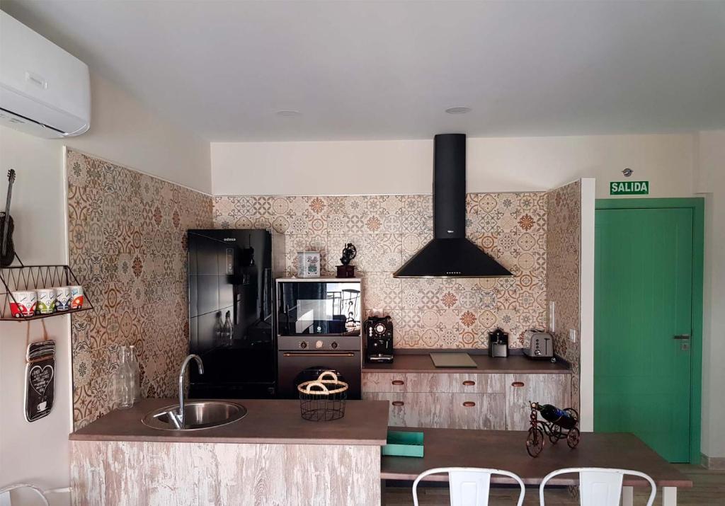 a kitchen with a black refrigerator and a green door at Apartamentos La Chaparrina del Jerte in El Torno