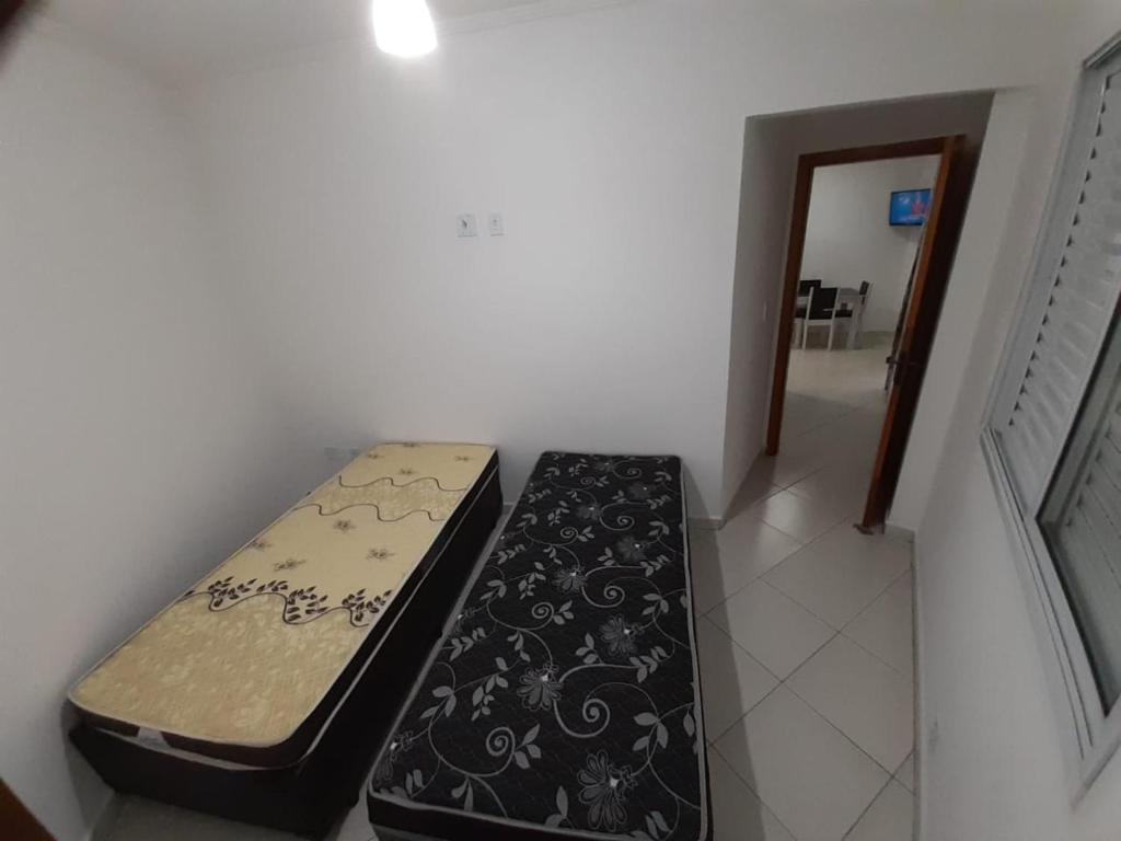 a bed sitting in a corner of a room at Apartamento 2 dorm na Guilhermina com tudo novo, Localização Incrível! Internet 200 MB in Praia Grande