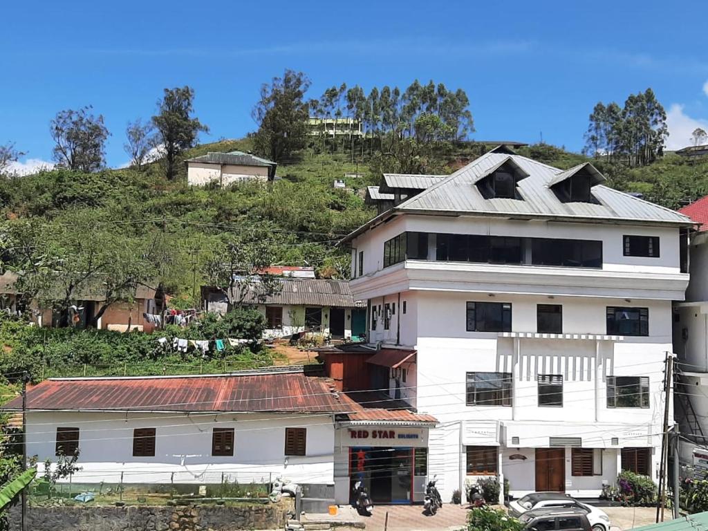 a white building with a roof on top of a hill at Red Star Holidays in Munnar