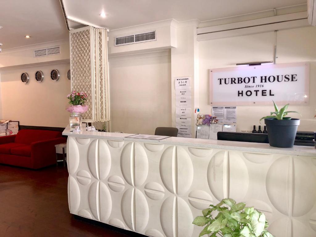 a hotel lobby with a counter and a red couch at Turbot House Hotel in Brisbane