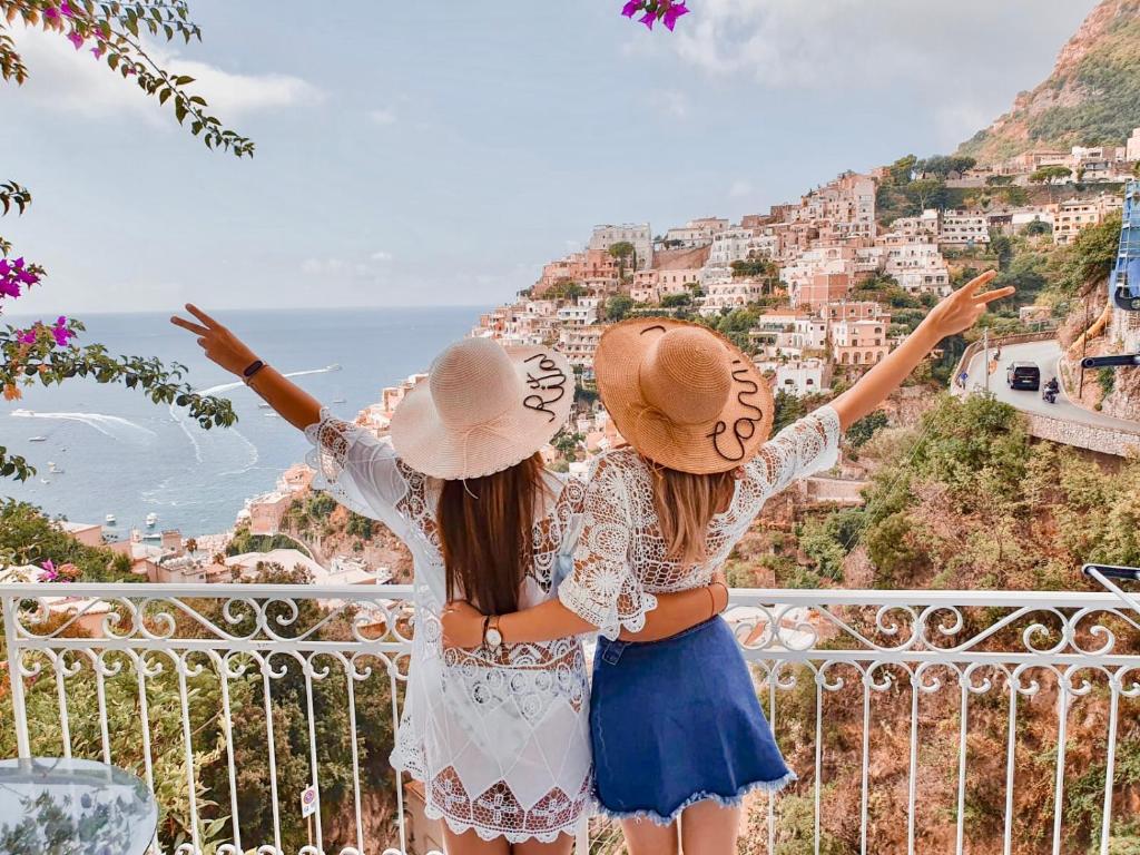 Santiago vacation home in Positano في بوسيتانو: بنتان واقفتان على شرفة تطل على المدينة