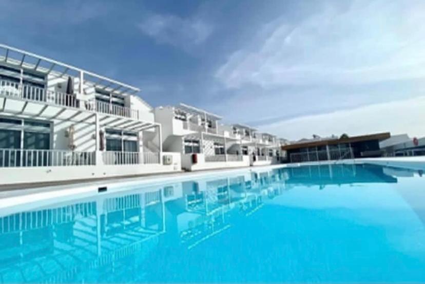 een zwembad met blauw water voor een gebouw bij Los Gracioseros in Puerto del Carmen