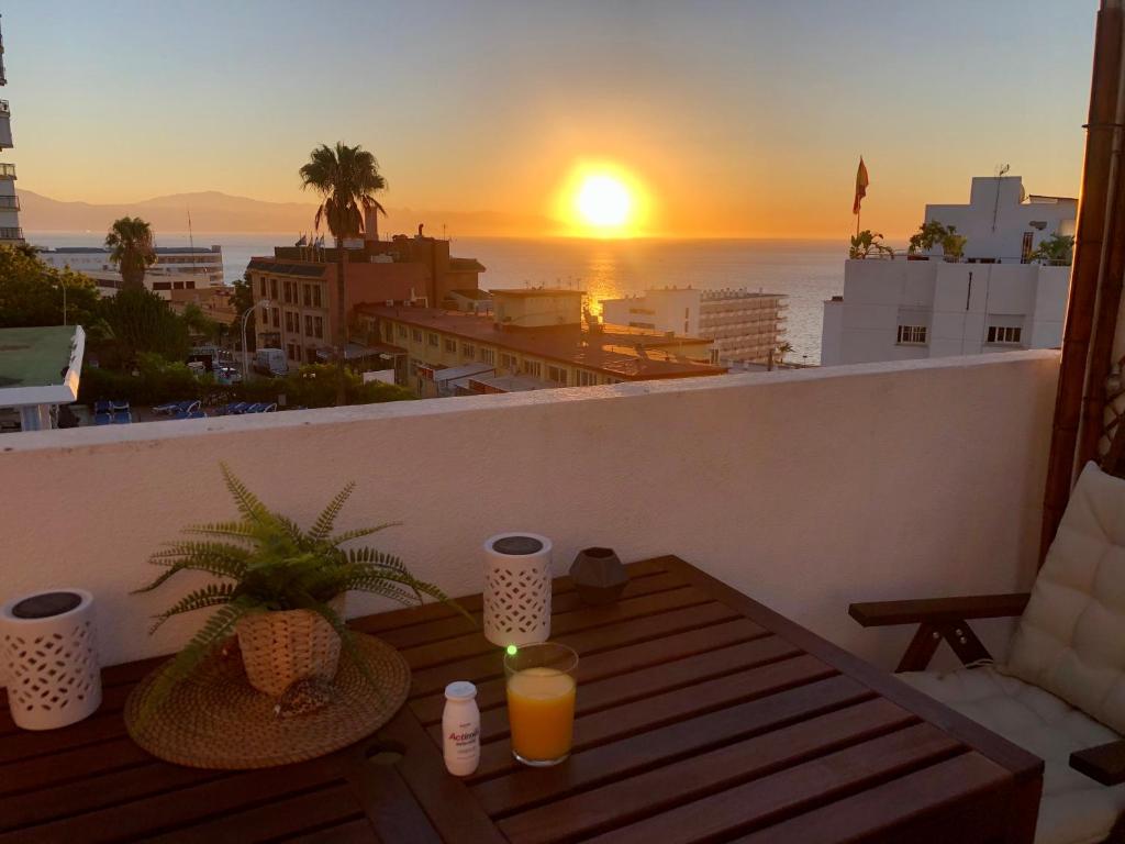 einen Sonnenuntergang auf einem Balkon mit einem Tisch und Getränken in der Unterkunft El Cortijuelo. Magnificent triplex terraced house with rooftop of 18m2, overlooking the sea. Parking in Torremolinos