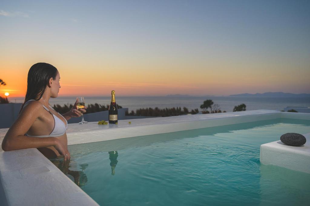 a woman standing in front of a pool of water at Santolia Art Suites in Oia