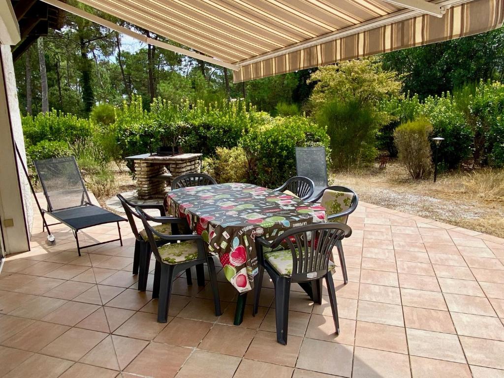 a table and chairs on a patio under a pergola at Cottage with a big idyllic garden at the lake in Lacanau