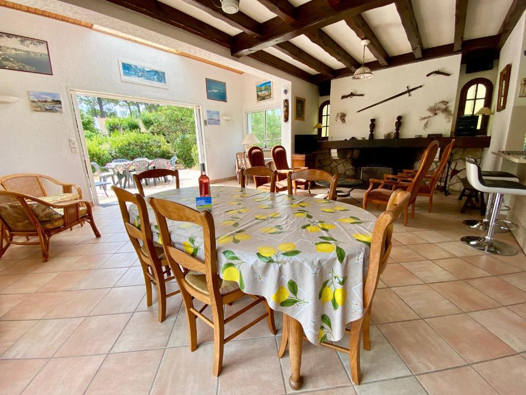 a dining room with a table and chairs and a fireplace at Cottage with a big idyllic garden at the lake in Lacanau