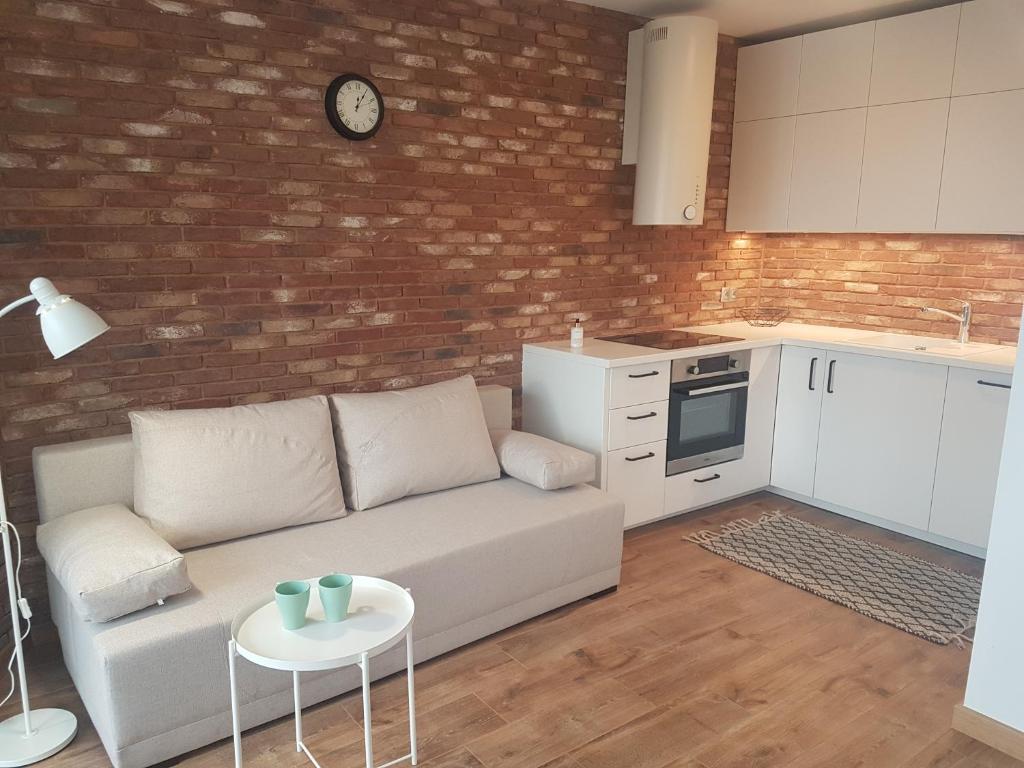sala de estar con sofá blanco y pared de ladrillo en Apartament Młynarska - indywidualny dostęp, en Piaseczno