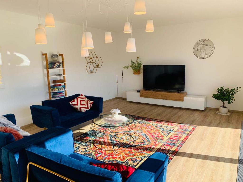 Apartment Am Kupferhammer في بفورتسهايم: غرفة معيشة مع اثنين من الأرائك الزرقاء وتلفزيون بشاشة مسطحة