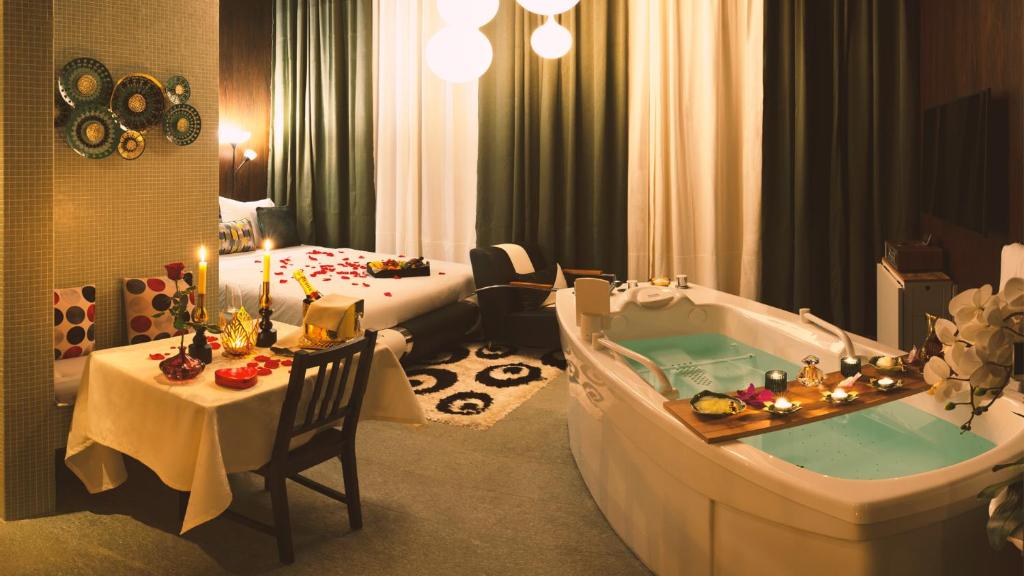 Habitación de hotel con bañera y dormitorio en Vitality Relax Spa Suite en Kloten