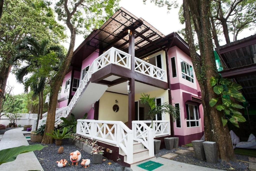 różowo-biały dom z drzewem w obiekcie Sandy House Rawai w mieście Rawai Beach