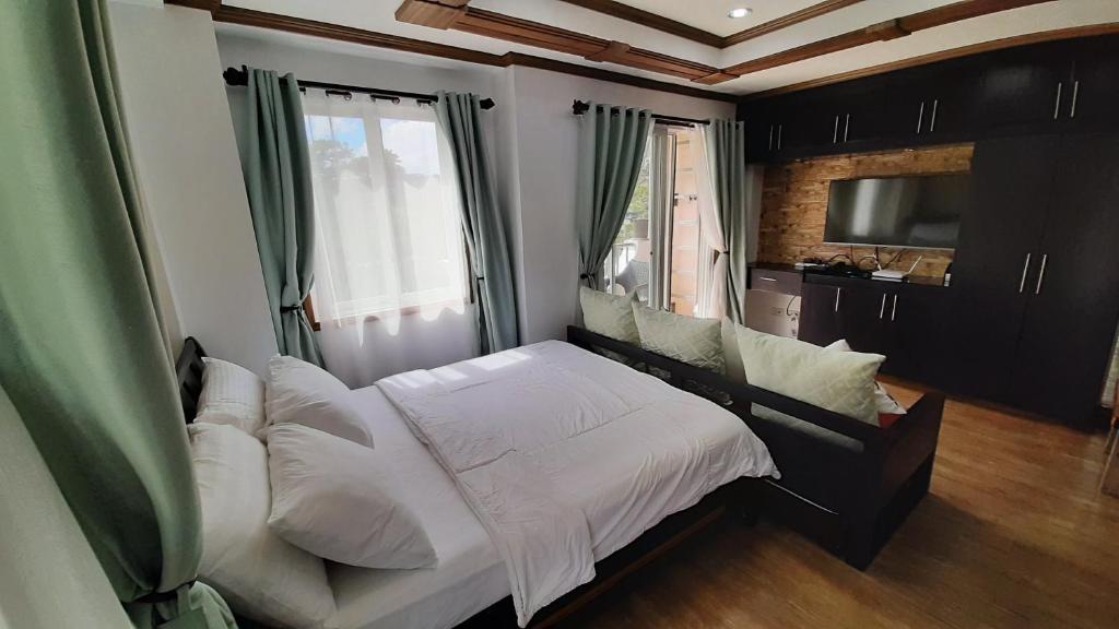 een slaapkamer met een bed, een bank en een televisie bij Gab's CozyHome at Bonbel Condo, Botanical Gardens Baguio in Baguio
