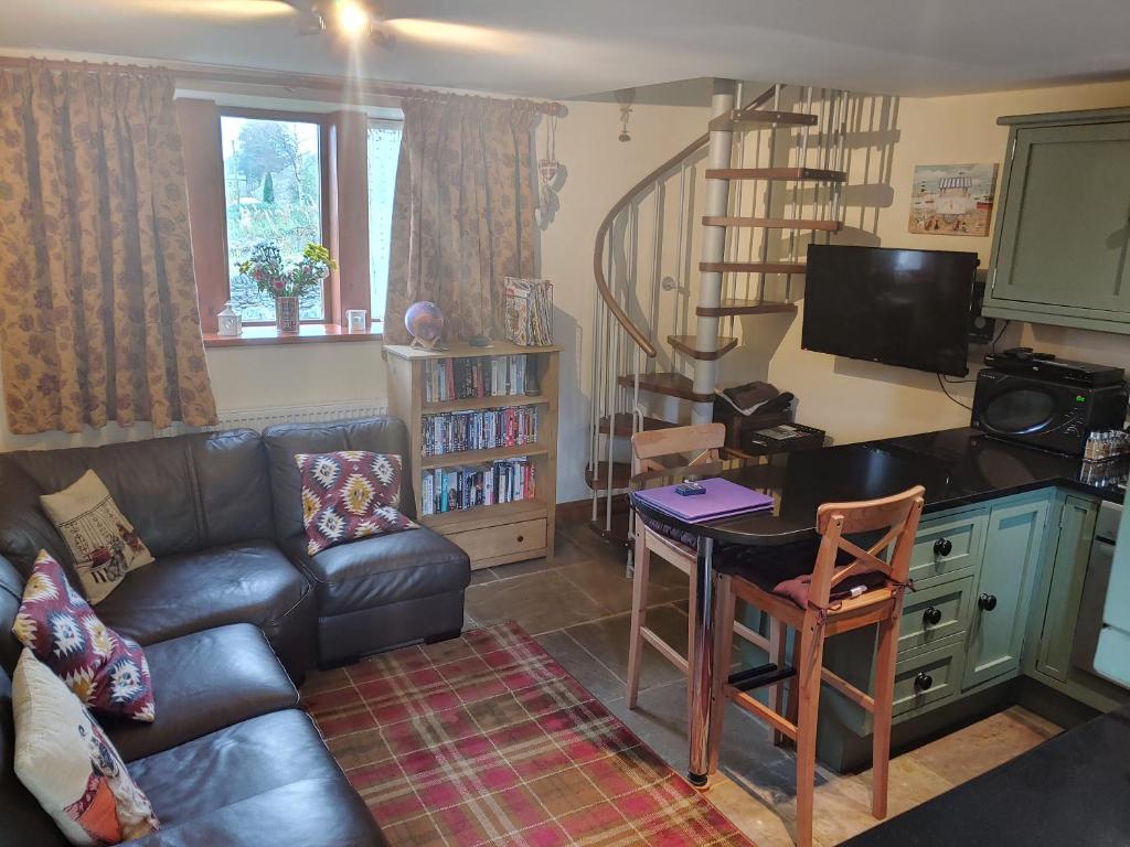 sala de estar con sofá de cuero y mesa en Pellcroft Cottage en Holmfirth