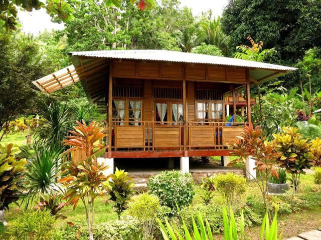 Bitung的住宿－Two Fish Resort Lembeh，一座小木房子,位于种有树木的花园内